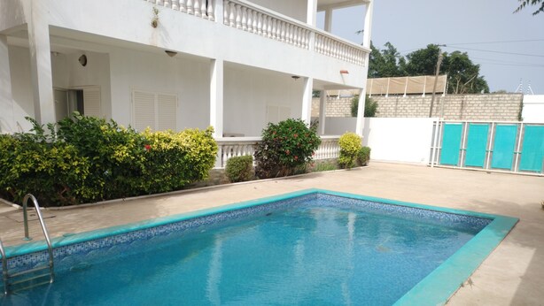 Une piscine rectangulaire dont le bord est recouvert de carreaux bleus, entourée d’une terrasse en béton.