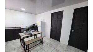 Una cocina con mesa de comedor, banco y puertas negras.