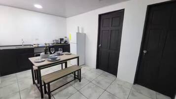 A kitchen with a dining table, bench, and black doors.