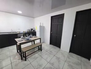 A kitchen with a dining table, bench, and black doors.