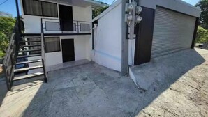 Un edificio de dos plantas con una puerta de garaje, una escalera y un poste de electricidad.