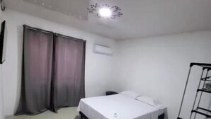 Una habitación pequeña y limpia, con una cama, un armario y una estantería metálica.