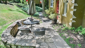 An outdoor patio with stone flooring, a round table, metal chairs, and a covered umbrella. - Historic Grove Park Rental - Apt #4 (Asheville)