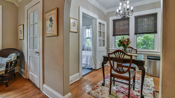 A room with a dining table, chairs, a chandelier, and a view of the outdoors through a window. - Historic Grove Park Rental - Apt #4 (Asheville)