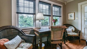 A room with a wooden table, wicker chairs, and a window with blinds. - Historic Grove Park Rental - Apt #4 (Asheville)