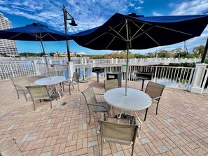 Une terrasse extérieure avec des tables et des chaises, des parasols et une vue sur l’eau.