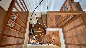 A spiral staircase with wooden railings and a central open area with a small table and chair. - Delightfully rustic 4-bedroom house in Vilas with stunning long-range views. (Vilas)