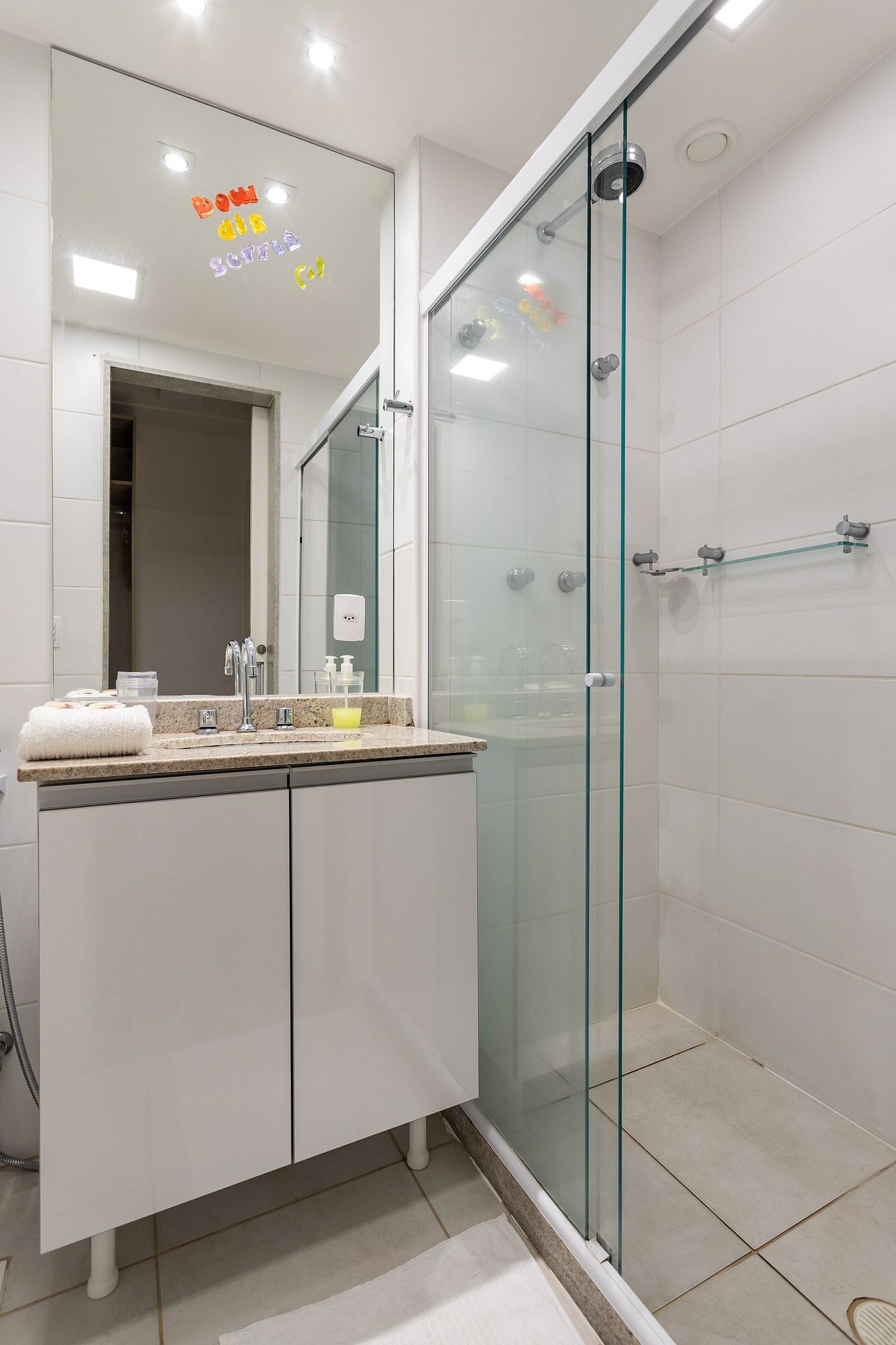 A modern bathroom with a glass-enclosed shower, a vanity with a sink, and a mirror above.