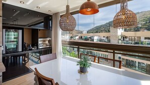 Et moderne køkken med spiseplads, store vinduer og en balkon med udsigt over byen.