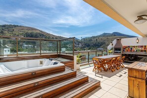 Eine Dachterrasse mit Whirlpool, Holzterrasse und Sitzbereich im Freien.