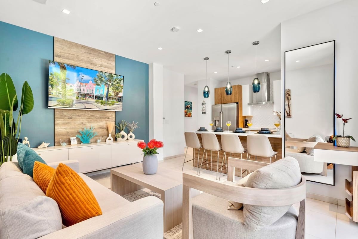 A modern living room with a sofa, coffee table, and a dining area with chairs and a table.