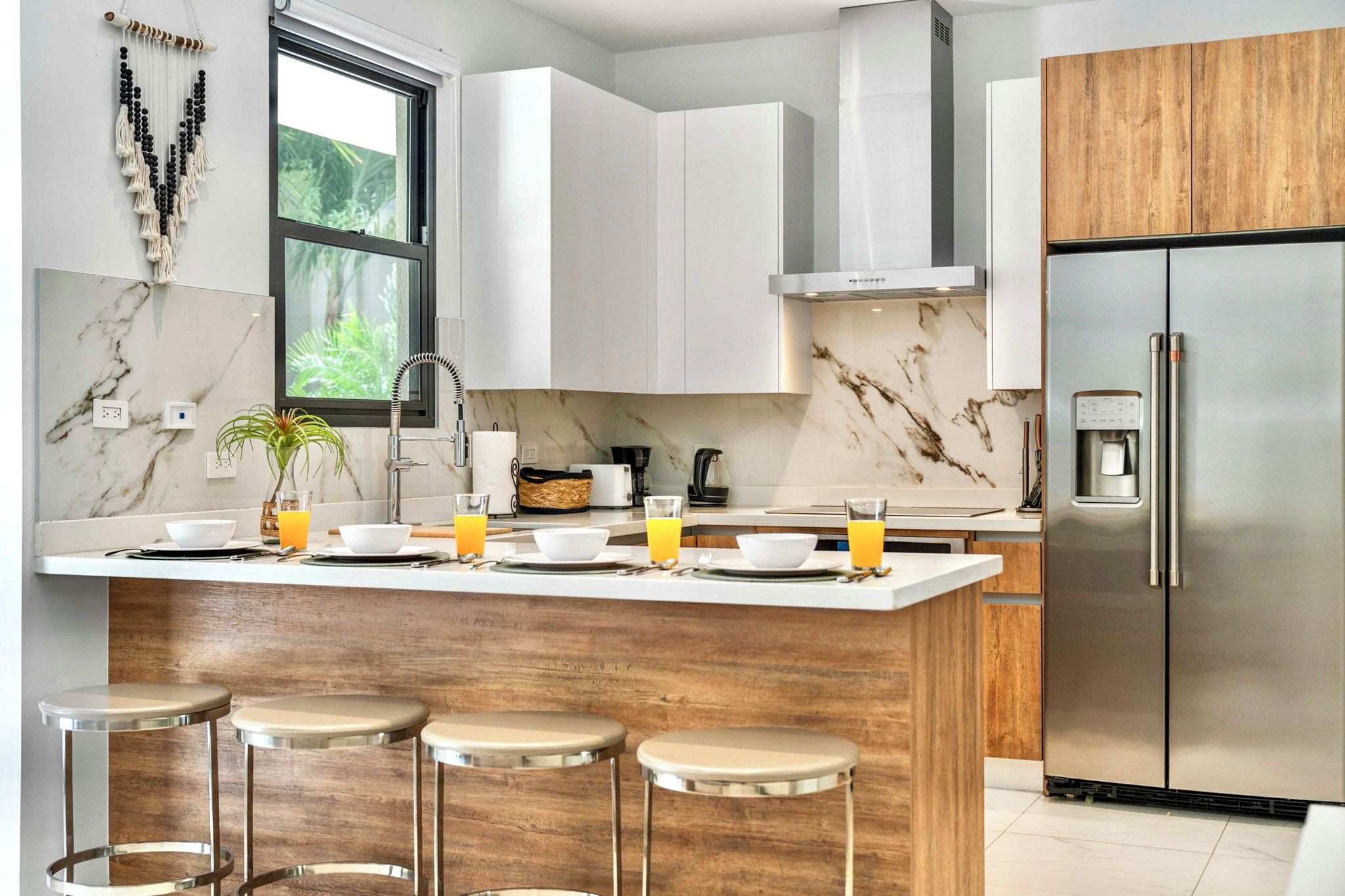 A modern kitchen with a marble backsplash, stainless steel appliances, and a central island with stools.