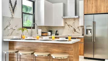 A modern kitchen with a marble backsplash, stainless steel appliances, and a central island with stools.