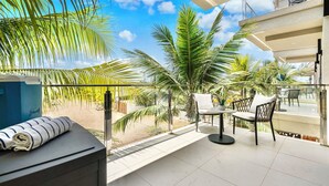 A balcony with a view of palm trees and a clear sky. - Wariruri Condos by SunStays (Noord)