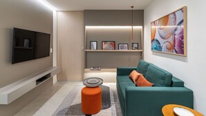 Ein modernes Wohnzimmer mit Flachbildfernseher, einem Türkis-sofa und einem Couchtisch.