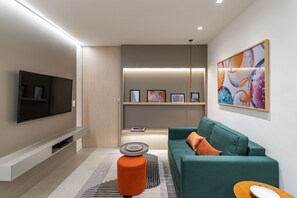 Un salon moderne avec un téléviseur à écran plat, un canapé de couleur turquoise et une table basse.
