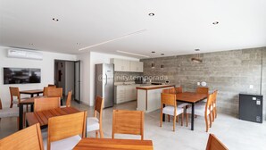 A modern kitchen with a stone backsplash, wooden dining table, and chairs.