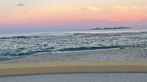 A beach with waves, a clear sky, and distant landforms. - 3-bedroom condo in enchanting Sint Maarten (Sint Maarten)