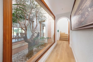 Un couloir avec un mur en verre, un plancher en bois et un escalier menant à un autre niveau.