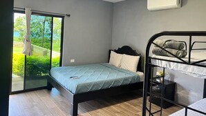 A bedroom with a single bed, a bunk bed, a window with curtains, and an air conditioning unit. - Rancho Agua Fria, Room #2 (Jucuaran)