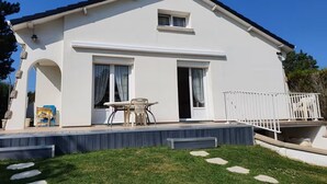 A two-story house with a balcony, a small porch, and a grassy yard. - Maison Sainte Cécile near beach and shops, pets welcome (Camiers)