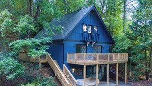 Une cabane bleue dotée d’une terrasse en bois et d’un escalier menant à un balcon situé à l’étage.