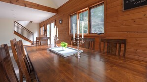 Une salle à manger en bois avec une grande table, des chaises et des bougies.