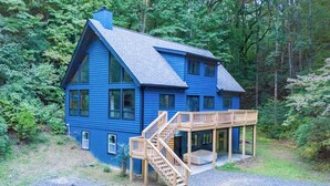 Une maison bleue avec une terrasse en bois et un escalier menant à un porche.