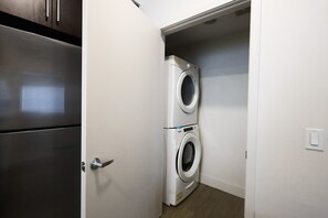 A laundry room with a washing machine and dryer, a door, and a light switch on the wall.