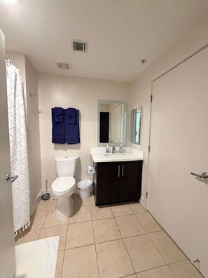Un baño con inodoro, lavamanos, espejo y toallero.