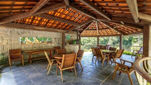 An outdoor patio with stone flooring, wooden furniture, and a tiled ceiling.