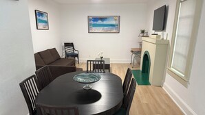 A dining area with a round table, chairs, a sofa, and artwork on the walls. - Lovely 2-bedroom house with AC in vibrant Miami (Miami)