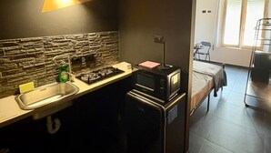 Een compacte keuken met een modern design, voorzien van een aanrecht van natuursteen, een spoelbak, een fornuis en een magnetron.