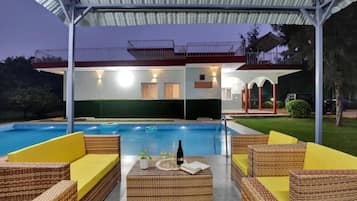 A poolside area with wicker furniture and a covered seating area.