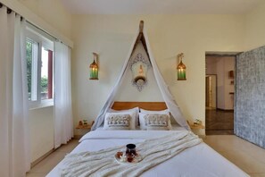 A bedroom with a canopy bed, bedside lamps, and a tray with drinks on the bed. - Alaya Stays By Elivaas Luxe Farm Acre - Manesar (Taoru)