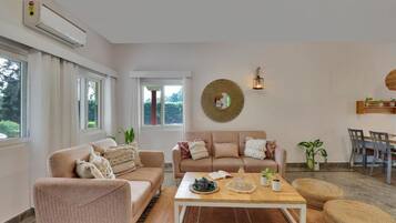 Een woonkamer met een bank, fauteuil, salontafel en een eethoek met stoelen en een tafel.