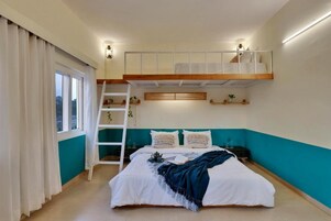Un dormitorio con una cama litera, una escalera, una ventana con cortinas y una pared de acento color turquesa.