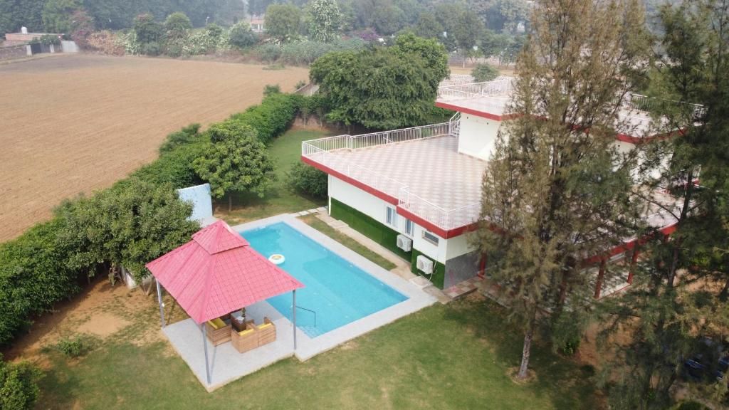 Una casa de dues plantes amb piscina, una glorieta amb teulada vermella i un pati tancat per una tanca.