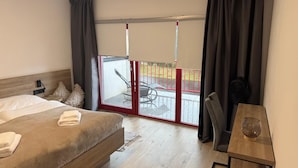 A hotel room with a bed, a desk, a chair, and a balcony with a table and chairs. - 4-Bedroom Luxury Apartment House with Café - 3 balconies with river view (Liberecký kraj)