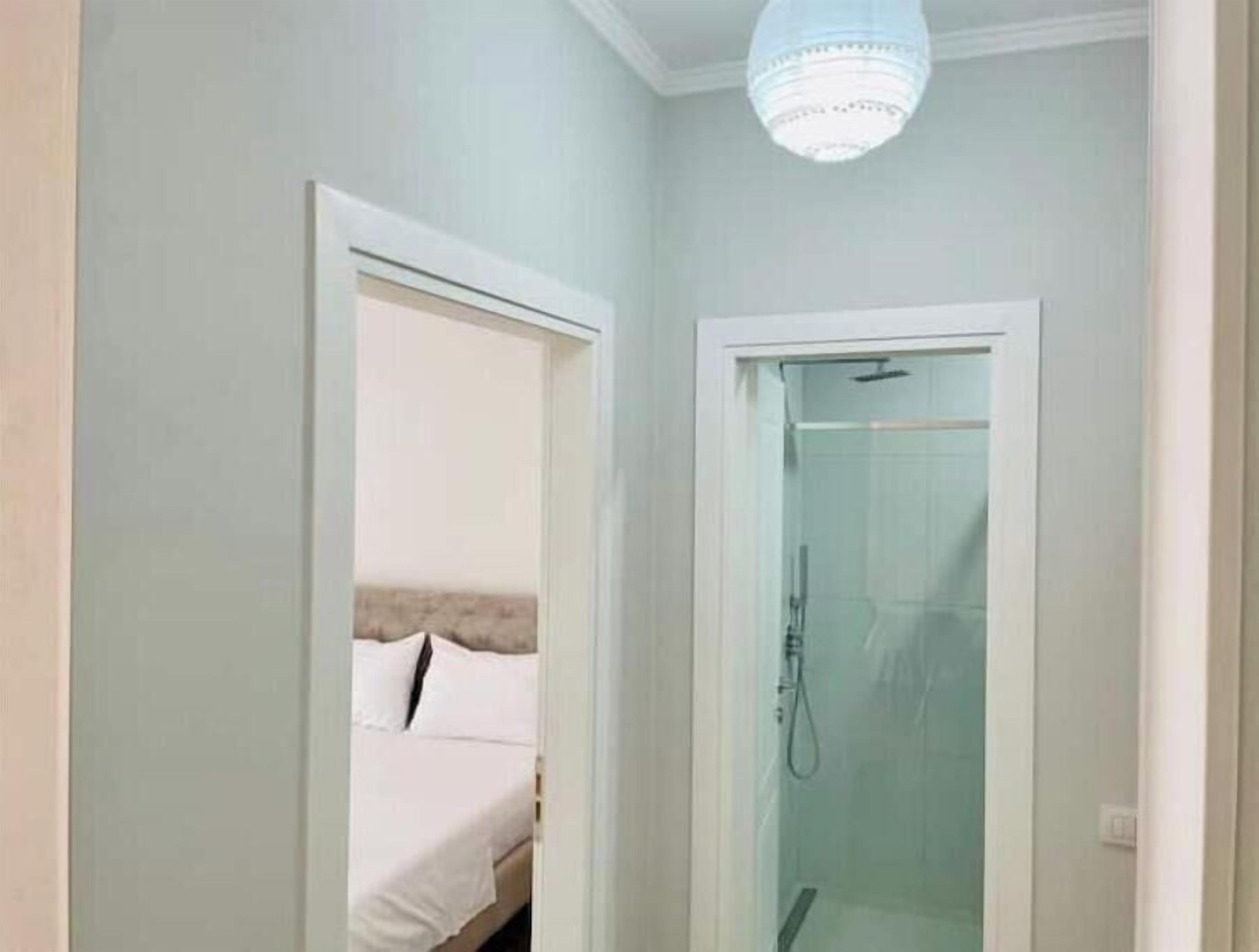 Een kamer met een bed, een glazen douchecabine en een hanglamp.