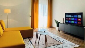 Una sala de estar moderna con un sofá, una mesita, un televisor y una planta en maceta.