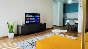 Una sala de estar moderna con un televisor de pantalla plana, una mesita redonda y un sofá amarillo.