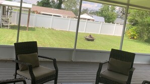 Un patio techado con mobiliario de mimbre y vista al jardín trasero.