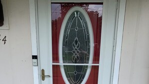 Una puerta principal con un panel de vidrio y un felpudo que dice "este es nuestro lugar feliz".