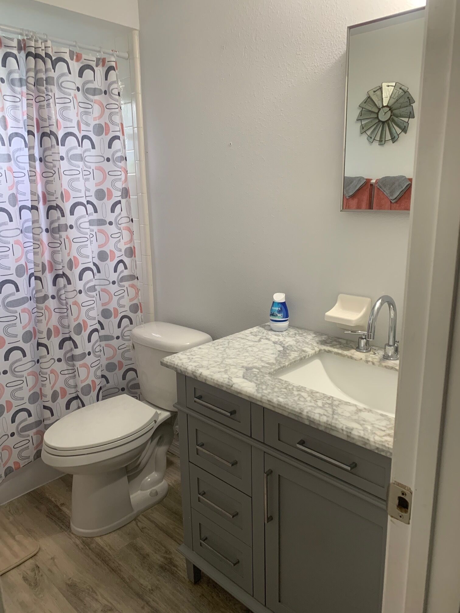 Een badkamer met toilet, wastafel, spiegel en een douchegordijn.