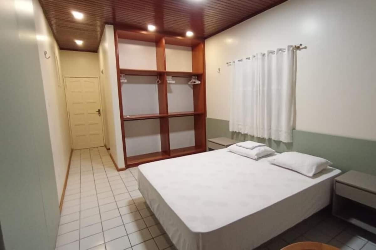 A bedroom with a bed, a nightstand, a wardrobe, and a shower curtain.