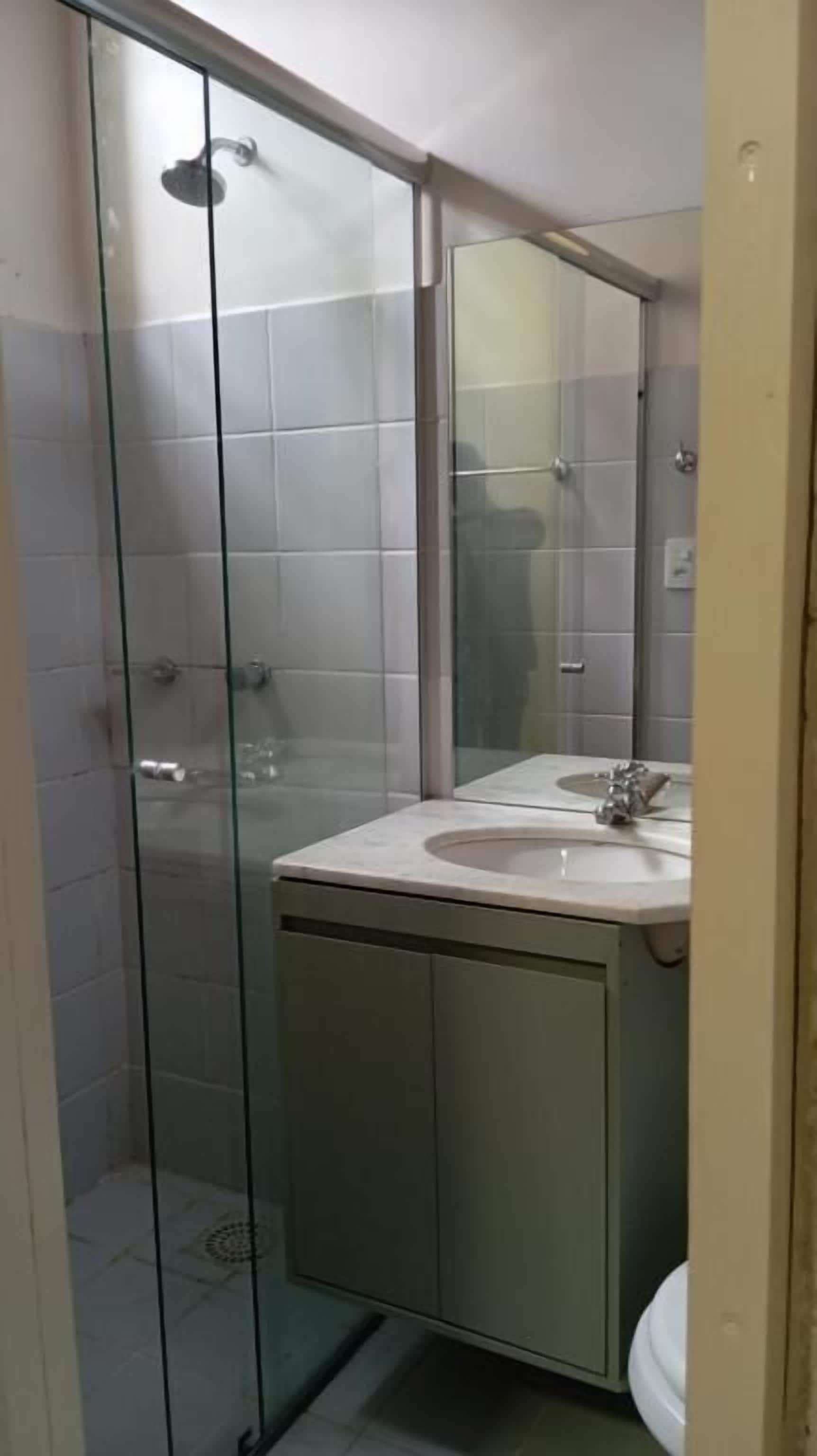 Un baño con cabina de ducha de vidrio, lavabo e inodoro.
