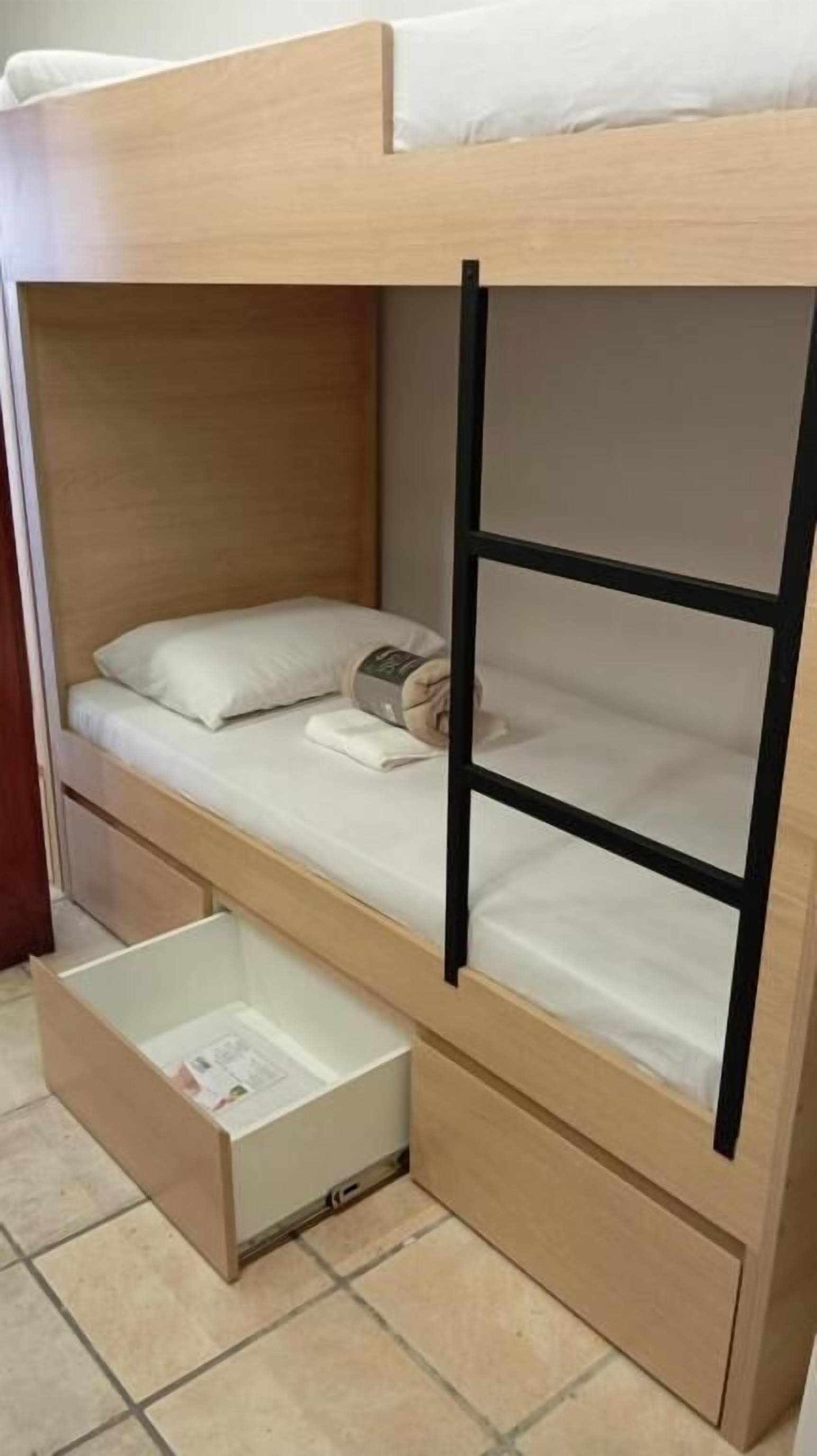 Un lit superposé avec un lit inférieur, un tiroir coulissant et un matelas avec des oreillers.