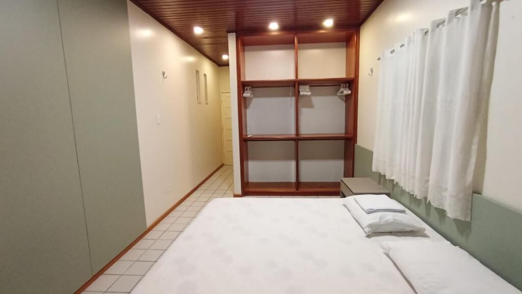 A bedroom with a bed, a wardrobe, and a shower curtain.