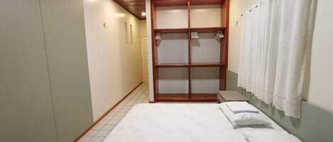 A bedroom with a bed, a wardrobe, and a shower curtain.